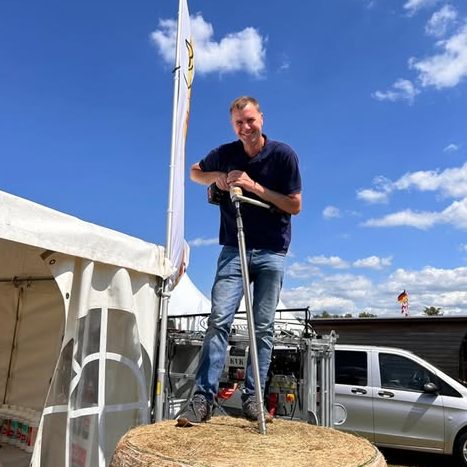 Siloprobenuntersuchung und Probenahme Thomas Kück steht auf einem Silageballen und bohrt eine Probe zum Untersuchen mit dem Nirssensor